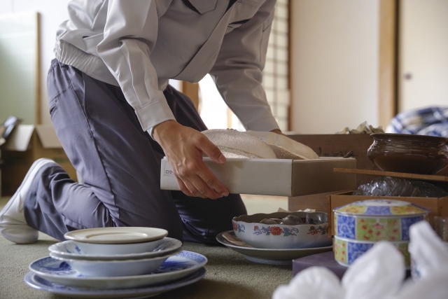 スタッフが和室で食器を一つひとつ丁寧に箱詰めして仕分けする様子